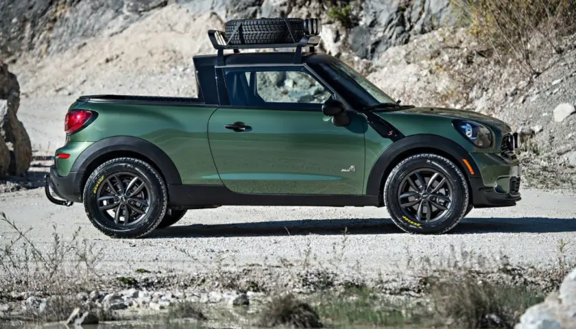 Zielony mini paceman z bagażnikiem dachowym i zapasowym kołem, gotowy na przygodę w terenie.