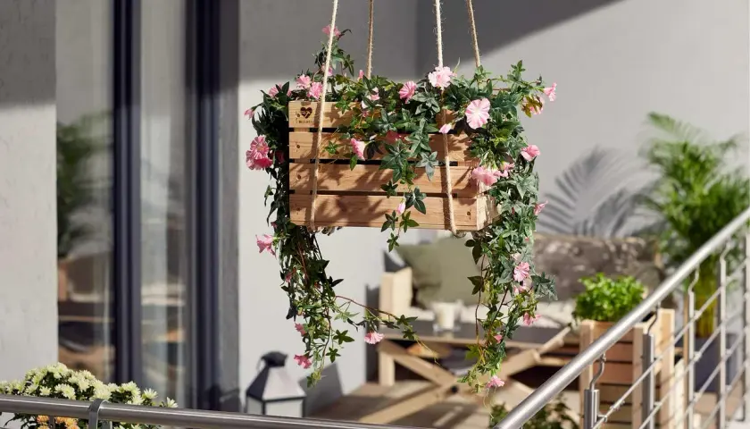 Jolie caisse en bois remplie de fleurs retombantes pour suspension, apportant une touche de couleur et de verdure à un balcon.
