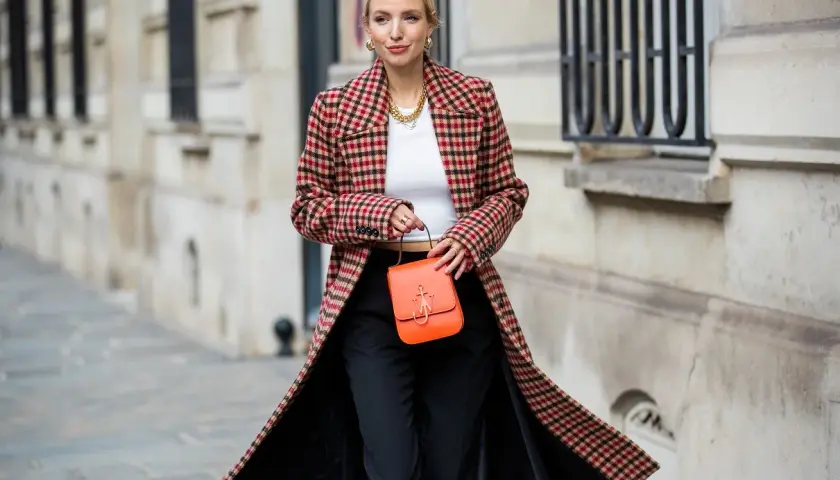 Elegancka kobieta w długim, kraciastym płaszczu damskim, z pomarańczową torebką.