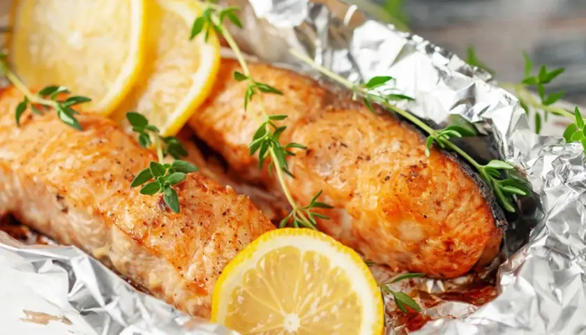Deux pavés de poisson, cuits en papillote sur la plancha, ornés de rondelles de citron et de brins de thym frais.