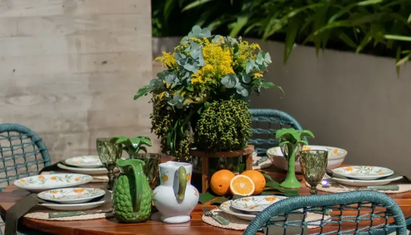 A vibrant tablescape with citrus-themed plates, green pitchers, and a lush floral arrangement. This modern everyday dining table decor evokes a fresh, summery feel.