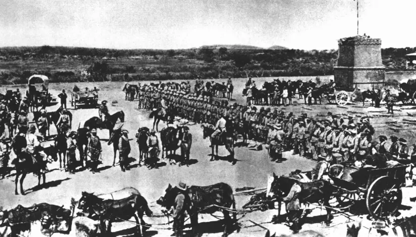 Soldaten und Pferde versammeln sich vor einem Turm. Die Szene erinnert an die Schlacht am Waterberg, ein entscheidendes Ereignis in der Kolonialgeschichte.