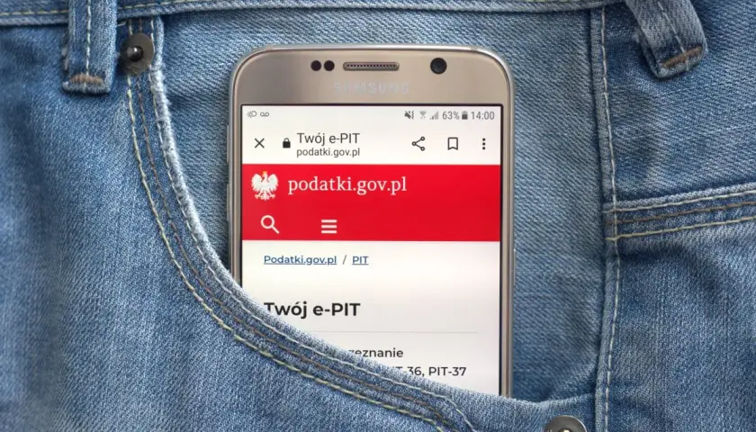 Telefon w kieszeni dżinsów wyświetla stronę podatki.gov.pl, gdzie można sprawdzić, jak zaokrąglić podatek od najmu.