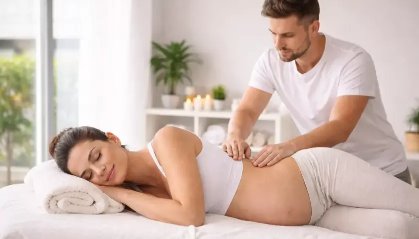 Donna incinta rilassata riceve un massaggio prenatale da un terapista esperto.