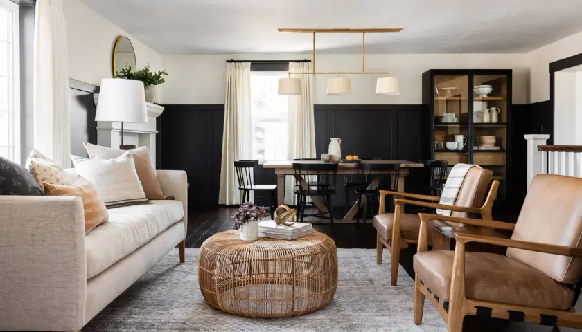 A living and dining space with a neutral palette and natural textures, embodying the mcgee and co style. A light-colored sofa, rattan coffee table, and leather armchairs create a cozy seating area.