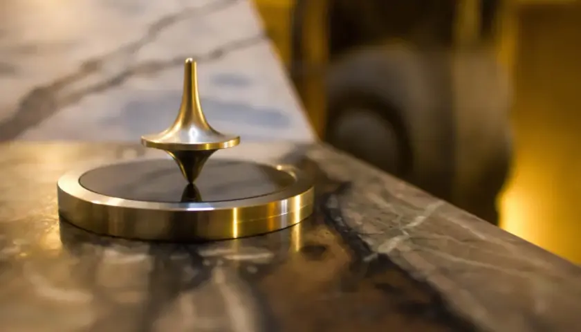 Toupie dorée en rotation, un exemple de force centrifuge qui maintient son équilibre.