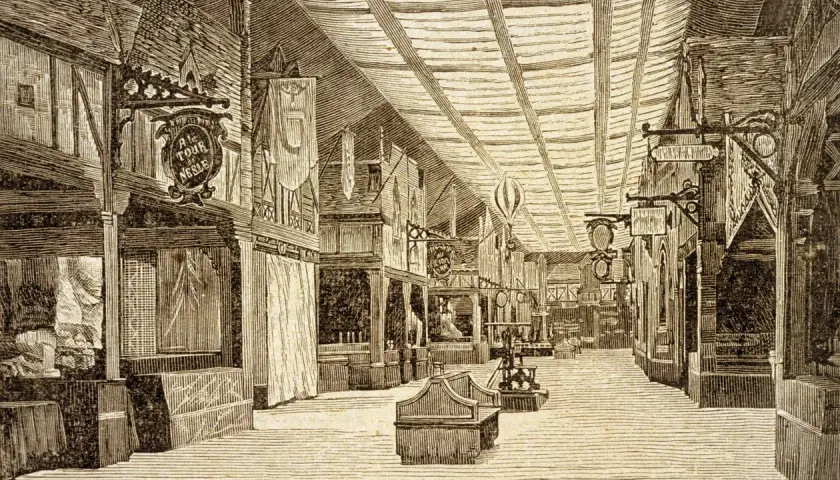 Bazar de la Charité: eine belebte Halle mit Ständen, Bannern und einem Heißluftballon.