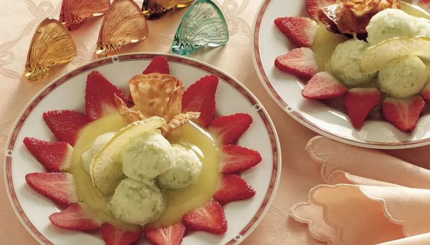 Delizioso sorbetto di mela servito con fragole fresche e una cialda croccante.