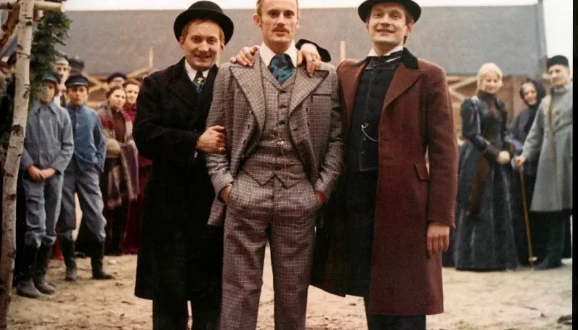 Trzech mężczyzn w melonikach i eleganckich strojach, jak z najlepsze filmy ranking. W tle tłum ludzi.