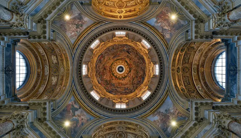 Soffitto affrescato di una delle magnifiche chiese barocche di Roma, con cupola centrale e decorazioni dorate.