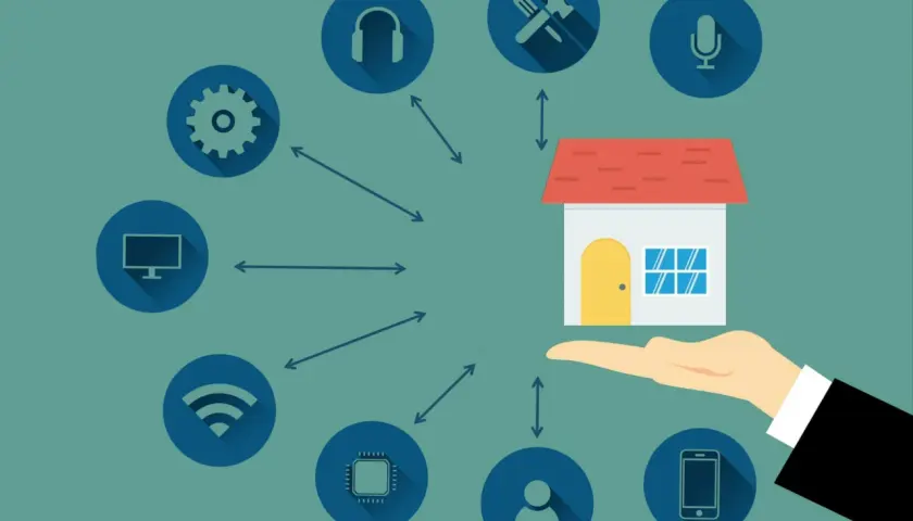 Una mano sostiene una casa conectada a iconos de tecnología, representando electrodomésticos domóticos que controlan el hogar inteligente.