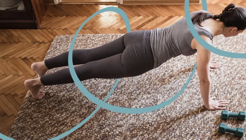 Kobieta w pozycji deski wykonuje jedno z 5 ćwiczeń pilates. Obok leżą hantle.