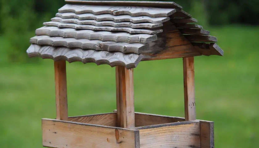 Drewniany karmnik dla ptaków diy, z dachem pokrytym łupkiem, gotowy na zimowych gości.