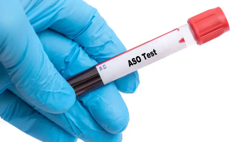 Ręka w niebieskiej rękawiczce trzyma probówkę z napisem "ASO Test".
