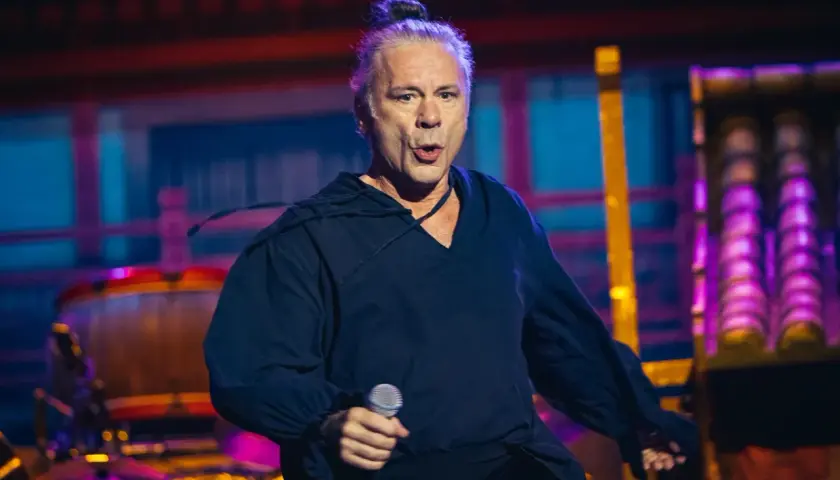 Bruce Dickinson, wokalista Iron Maiden, śpiewa z mikrofonem na koncercie.