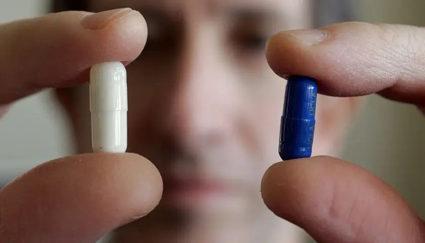Dita tengono una pillola bianca e una blu, forse per uno studio sull'effetto placebo.