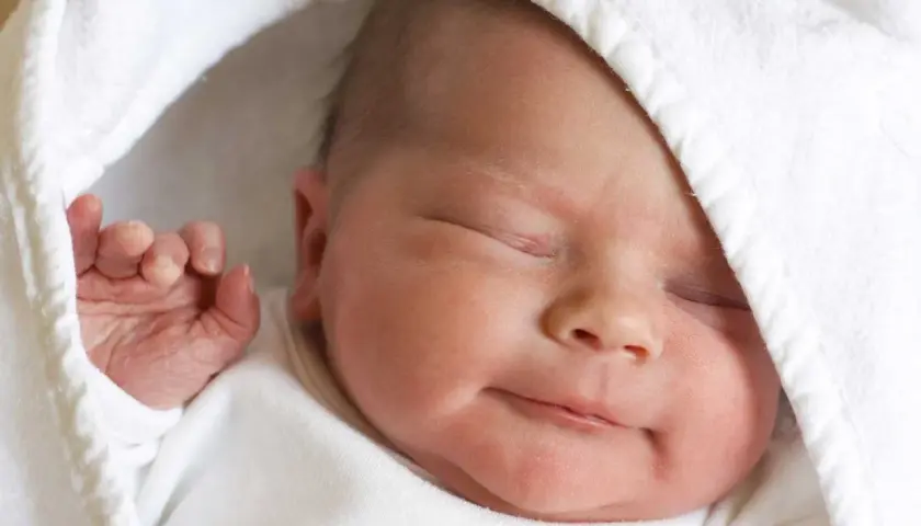 La morbida pelle neonato, avvolta in un soffice asciugamano bianco, dorme serenamente.