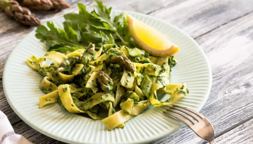 Pappardelle z zielonym sosem, szparagi i rukola na talerzu. Pyszny makaron ze świeżymi warzywami.