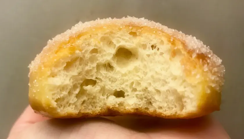 Gros plan d'un beignet sucré, sa mie aérée parfaite pour une recette beignet maison.