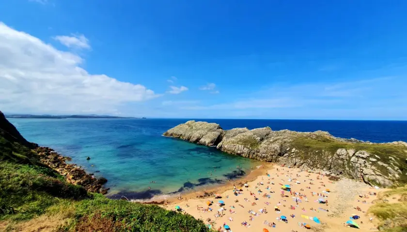 Vista aérea de la playa de Somo, con gente disfrutando del sol y el mar. Las reseñas de la playa de Somocuevas la describen como un paraíso.