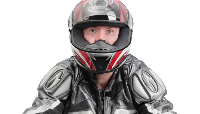 Occhi spalancati dietro un casco stretto, pronto per la corsa. La tuta in pelle grigia e nera completa il look da motociclista.