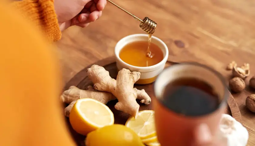 Zutaten für hustentee selber machen: Ingwer, Zitrone, Honig und eine Tasse Tee.