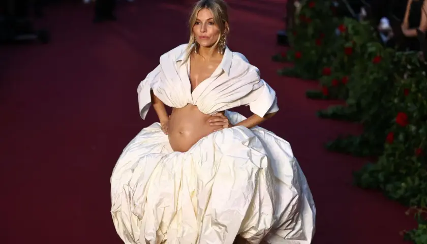 Jodie Turner-Smith, embarazada, luce un voluminoso vestido blanco con escote pronunciado y falda abullonada sobre una alfombra roja.