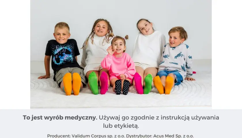 Pięcioro dzieci siedzi na podłodze, prezentując kolorowe skarpetki na stopach.