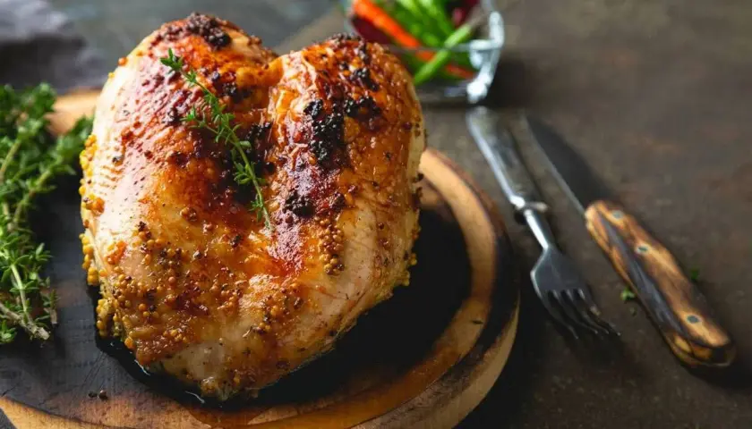 Succulento petto di pollo al forno, dorato e speziato, pronto per essere gustato con erbe aromatiche e peperoncini.