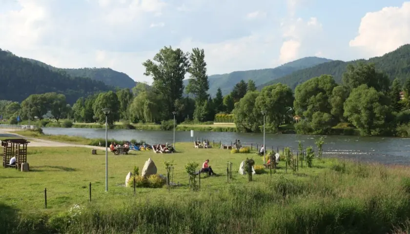 Relaks nad Dunajcem w Krościenku. Ludzie odpoczywają na trawie, w tle góry i rzeka. To świetne krościenko nad dunajcem atrakcje.
