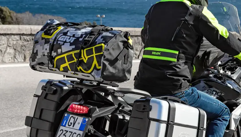 Motociclista con equipaje en maletas laterales y bolsa trasera. Es correcto transportar el equipaje en maletas laterales para viajes largos.