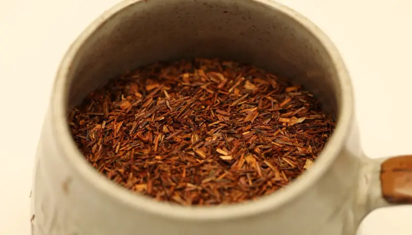 Czerwona herbata rooibos w ceramicznym kubku, idealna na relaksujący wieczór.