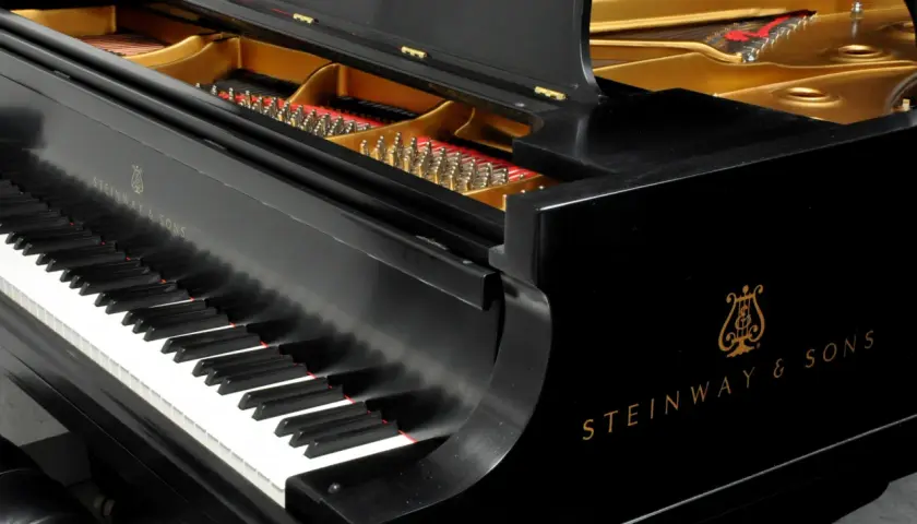 Czarne pianino Steinway & Sons z otwartą klapą, ukazującą struny i złote wnętrze. Zastanawiasz się, ile waży płyta mosiężna w pianinie?