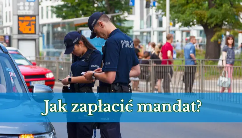 Dwóch policjantów w mundurach dyskutuje, jak zapłacić mandat online. W tle widać ludzi i budynki.