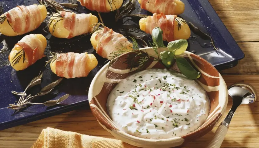 Leckere Kartoffeln im Speckmantel mit Kräutern und einem Dip.