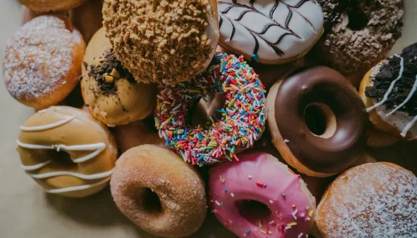 Kolorowe pączki z posypką, lukrem i cukrem pudrem. Każdy pączek to mała przyjemność, ale warto pamiętać o jego pączek kcal.