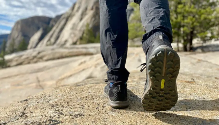 Close-up of hiking boots on a rocky trail, showcasing the aggressive boot tread patterns designed for grip on uneven terrain.