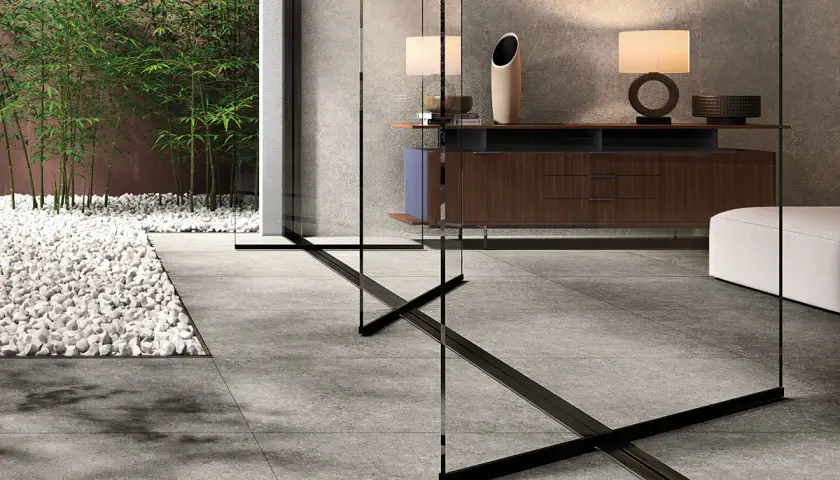Un elegante soggiorno con arredi moderni e un giardino zen con bambù, evocando la raffinatezza del cotto d'Este.