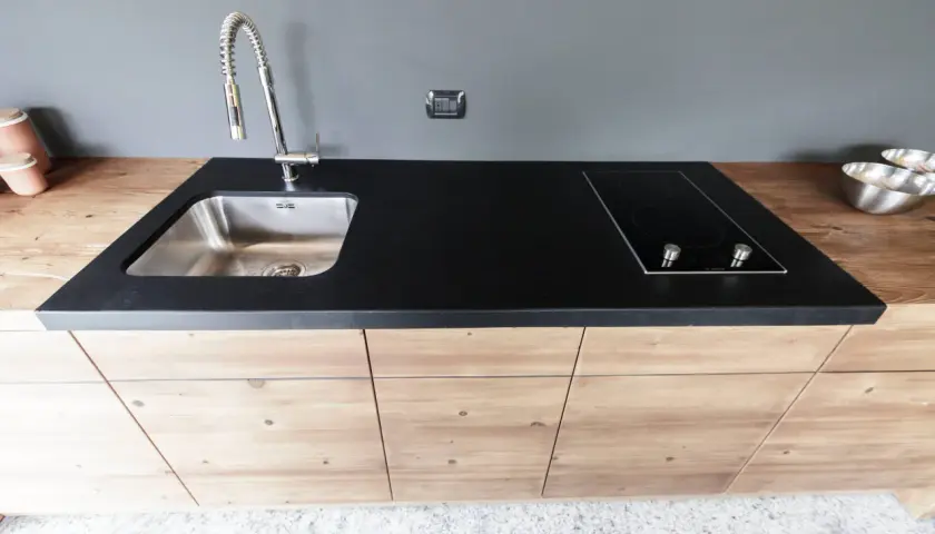 Mobile lavello cucina fai da te con piano in pietra nera, piano cottura a induzione e rubinetto cromato.