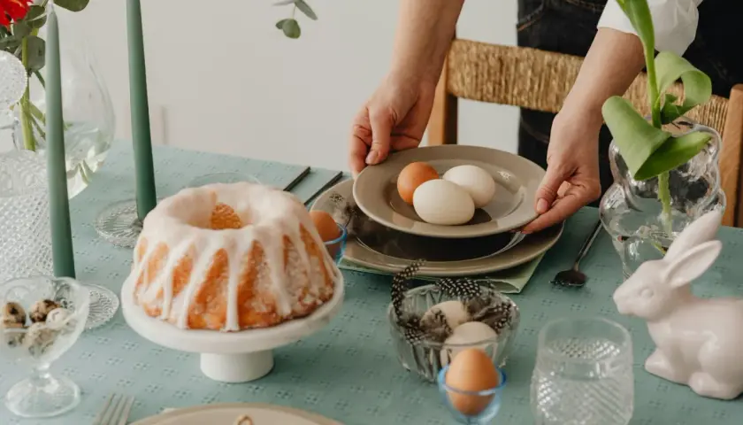 Tavola apparecchiata per Pasqua con un ciambellone glassato, uova e decorazioni. I dolci pasquali sono pronti per essere gustati.