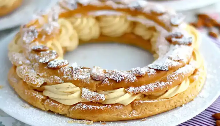Un Paris-Brest, pâtisserie en forme de couronne, garni d'une crème onctueuse et saupoudré d'amandes effilées et de sucre glace.