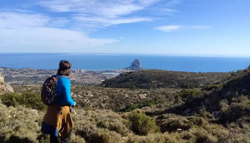 Senderista contempla el Peñón de Ifach y la costa desde una de las rutas de Calpe.