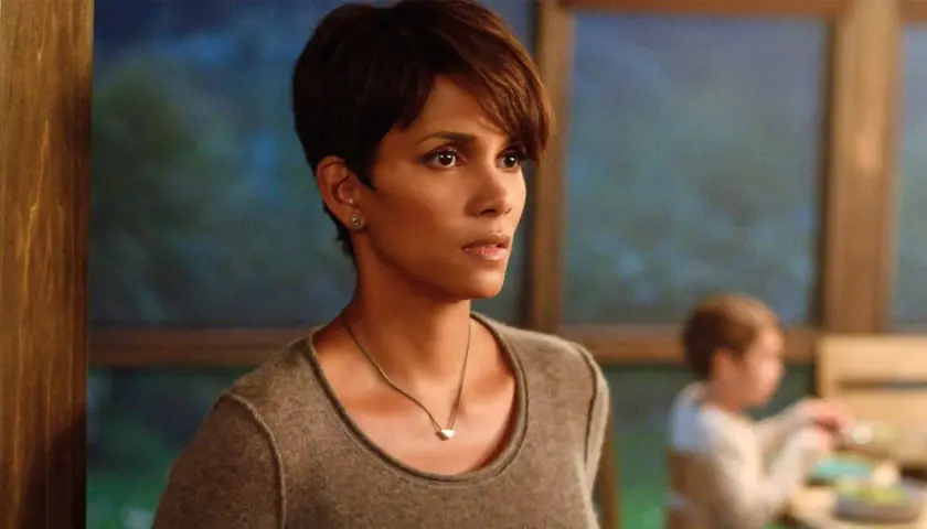 Halle Berry w filmie, zamyślona, w tle niewyraźne dziecko.