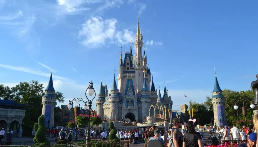 Tłum ludzi spaceruje przed zamkiem w Disneylandzie, gdzie marzenia stają się rzeczywistością.