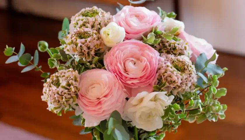 Un bouquet de fleurs roses et blanches, composé de renoncules et d'hortensias, prêt à être ajouté à la liste de souhaits du fleuriste.