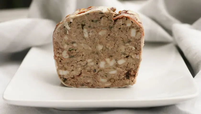 En bit rustik lantpaté med synliga bitar av fett och örter, perfekt för ett lantpaté recept.