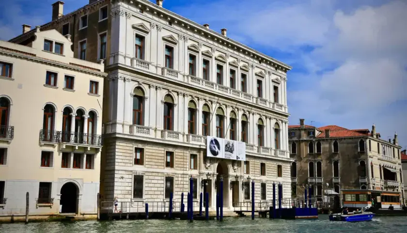 Le **Palazzo Grassi** à Venise, majestueux édifice blanc, se reflète dans le Grand Canal. Une exposition Irving Penn y est annoncée.