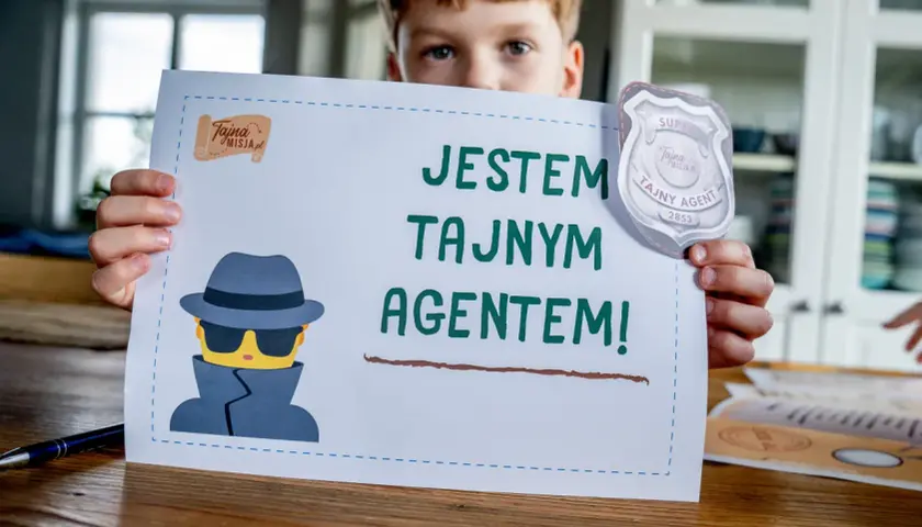 Chłopiec trzyma kartkę z napisem "Jestem tajnym agentem!" i rysunkiem szpiega. Idealne do gry szpiegowskie.