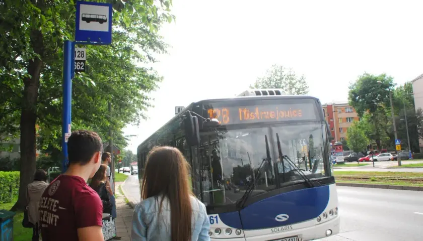 Autobus MPK na przystanku z pasażerami, znak z ikoną autobusu.