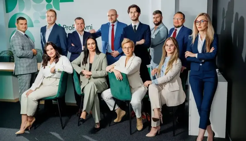 Zespół prawników w eleganckich garniturach pozuje do zdjęcia.